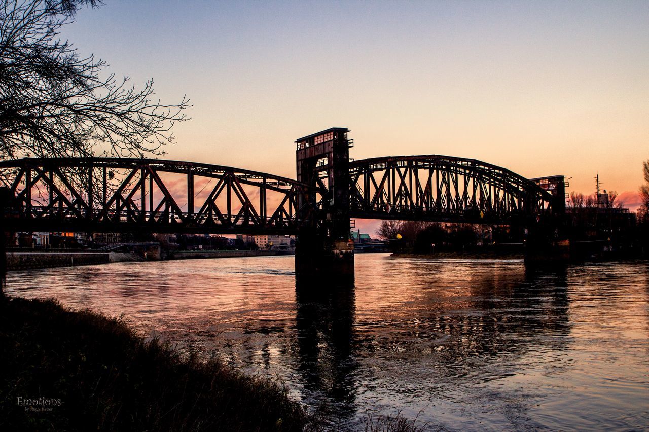 BRIDGE OVER RIVER WITH CITY IN BACKGROUND