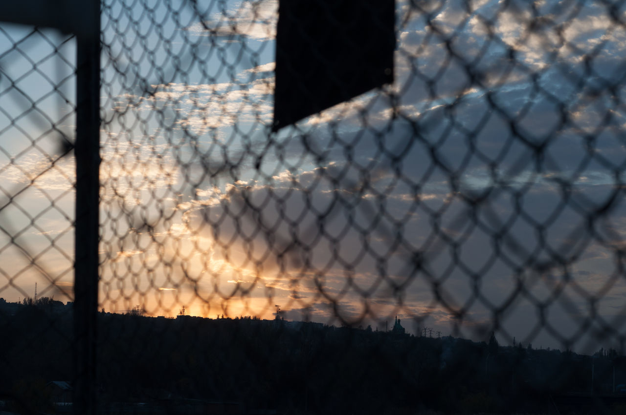 CLOSE-UP OF CHAINLINK FENCE AT SUNSET