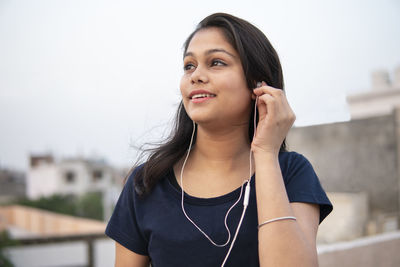 Portrait of smiling young woman standing against blurred background