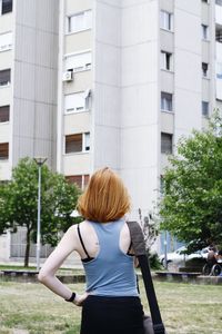 Rear view of woman standing on grass against building