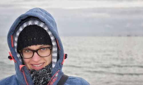 Portrait of smiling young woman wearing sunglasses against sea