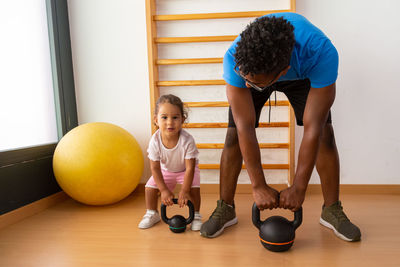 Little kid lifting kettlebell near father