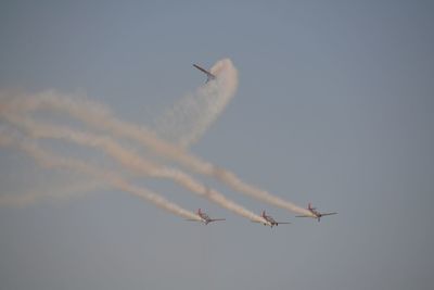 Low angle view of airplanes flying against sky