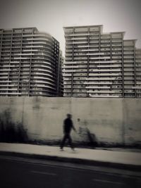 Blurred motion of person walking on street against buildings in city