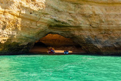 People on boat over sea in cave