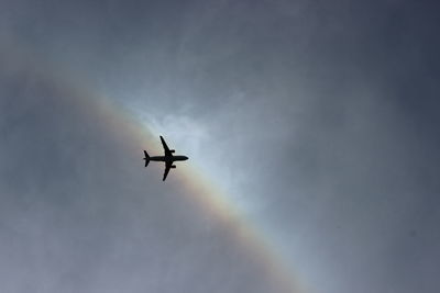 Directly below shot of airplane in sky against rainbow