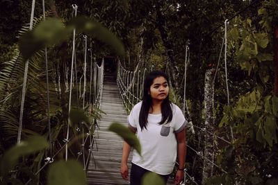 Young woman standing against trees in forest