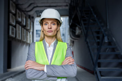 Portrait of young woman standing against building