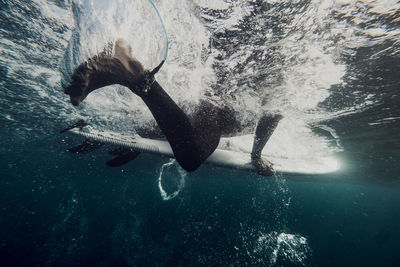 Underwater close up of a surfer on his surfboard