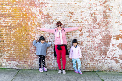 Full length of women standing against pink wall