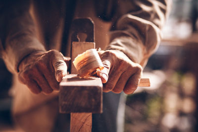 Midsection of carpenter using plane on wood