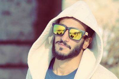 Portrait of young man wearing sunglasses while standing outdoors during sunny day