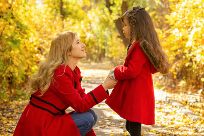 Side view of two women standing on autumn leaves