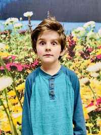 Portrait of boy standing by flowering plants