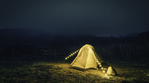 Illuminated tent on field against sky at night