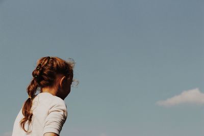 Low angle view cute girl looking away while standing against sky