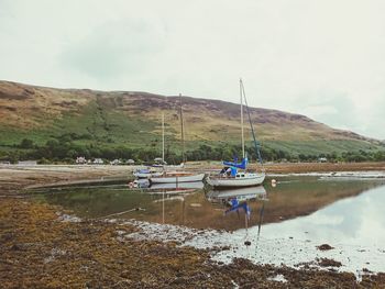 Boats moored in lake against sky