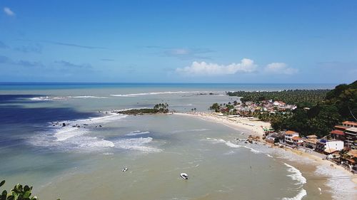 People swimming in sea against blue sky