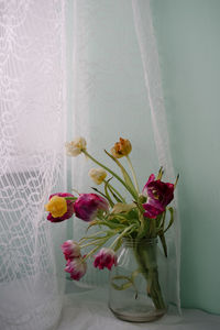 Close-up of flower vase on table against wall