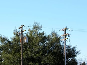 Low angle view of electricity pylon against clear blue sky
