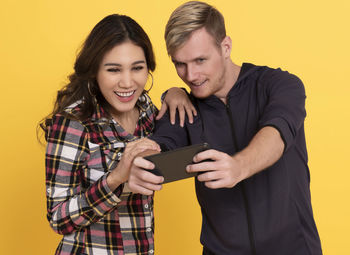 Young couple holding hands against yellow background