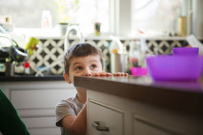 Boy hiding and playing in kitchen at home