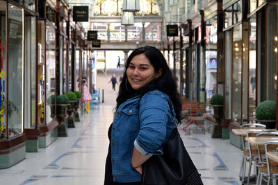 Portrait of smiling young woman standing in shopping mall