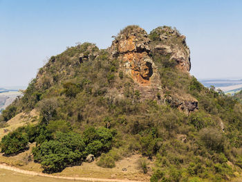 Scenic view of cliff by sea against clear sky
