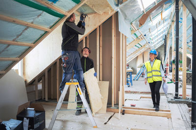 Female manager looking at manual workers working in construction site