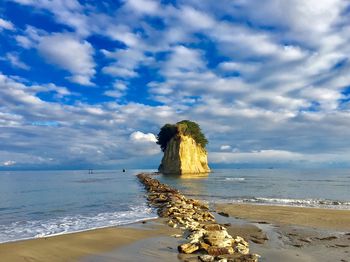 Rear view of rock on beach against sky