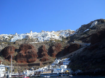 Buildings by mountain against clear blue sky