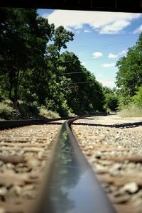 Surface level of railroad track in canal against sky