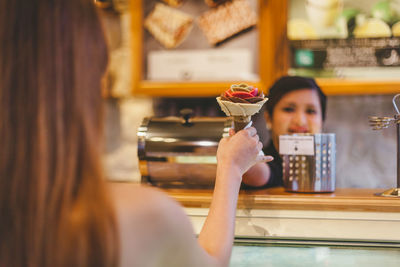 Portrait of woman holding ice cream in cafe