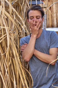 Young man standing by dry plants at farm