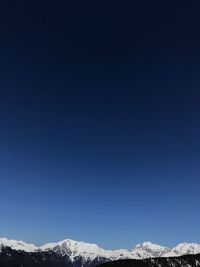 Scenic view of snowcapped mountains against clear blue sky
