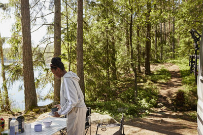 Woman collecting dishes from camping table