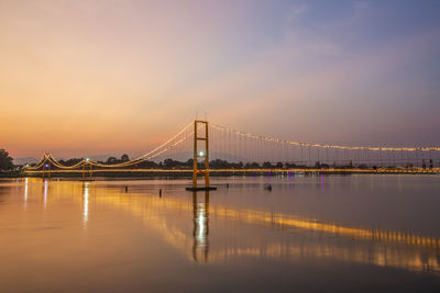 View of suspension bridge over river at sunset