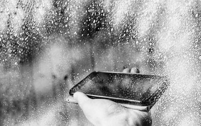 Close-up of hand on wet window