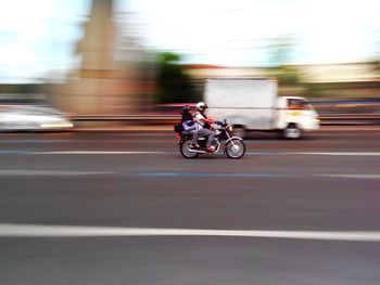 Blurred motion of people riding motorcycle on road