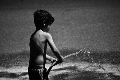 Full length of shirtless boy standing on field