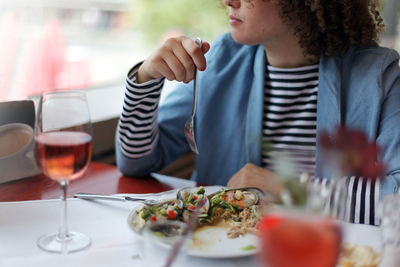 Midsection of woman having food in plate at restaurant