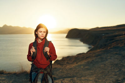 Portrait of smiling young woman standing on shore