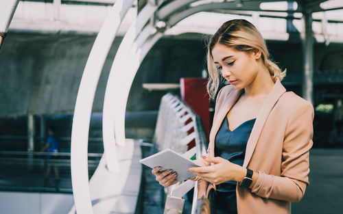 Woman looking at camera while standing on mobile phone