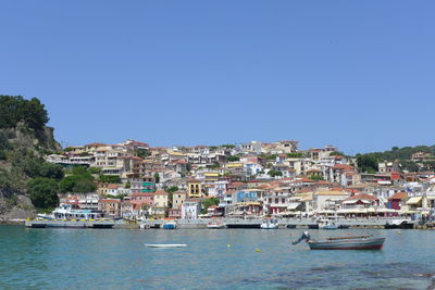 Sailboats in sea by townscape against clear blue sky