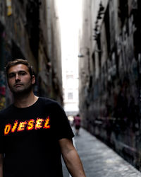 Portrait of young man standing on street in city