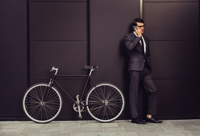 Full length of man with bicycle against wall