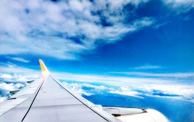 Airplane flying over cloudscape against blue sky