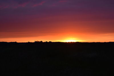 Silhouette landscape against dramatic sky during sunset