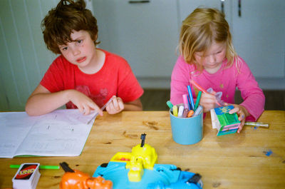 Siblings drawing on table