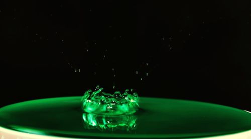 Close-up of drop falling on water against black background